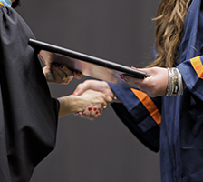 Photo: a graduate's hand receiving a diploma and shaking hands