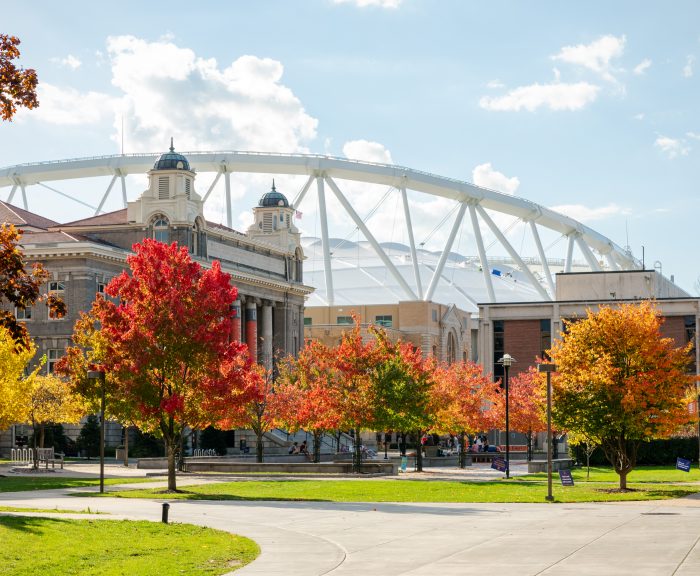 Autumn trees with vibrant colors on the quad with Carnegie Library and the stadium in the background.